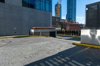 a parking lot next to tall buildings and a street corner under a bright blue sky