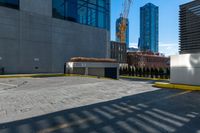 a parking lot next to tall buildings and a street corner under a bright blue sky