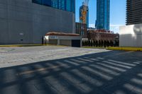 a parking lot next to tall buildings and a street corner under a bright blue sky