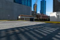 a parking lot next to tall buildings and a street corner under a bright blue sky