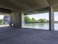 a concrete room with a circular open door and a bench in front of a pond