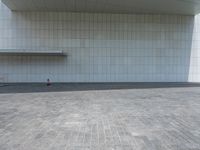 a person sitting on the curb and facing a wall with an empty space for sitting