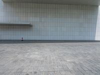 a person sitting on the curb and facing a wall with an empty space for sitting