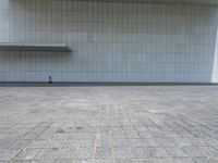 a person sitting on the curb and facing a wall with an empty space for sitting