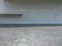 a person sitting on the curb and facing a wall with an empty space for sitting