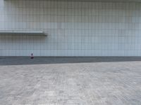 a person sitting on the curb and facing a wall with an empty space for sitting