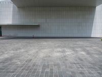 a person sitting on the curb and facing a wall with an empty space for sitting