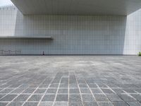 a person sitting on the curb and facing a wall with an empty space for sitting