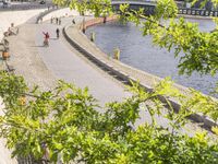 people riding bikes by the river while walking on it's side in the day