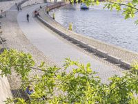 people riding bikes by the river while walking on it's side in the day