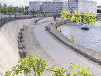 people riding bikes by the river while walking on it's side in the day