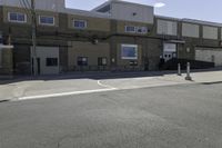 a motorcycle rider and another street sign sit in front of an industrial building on an empty street