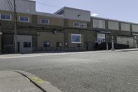 a motorcycle rider and another street sign sit in front of an industrial building on an empty street