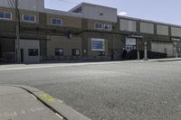 a motorcycle rider and another street sign sit in front of an industrial building on an empty street