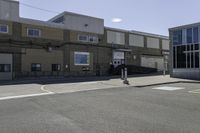 a motorcycle rider and another street sign sit in front of an industrial building on an empty street