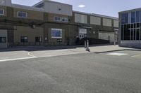 a motorcycle rider and another street sign sit in front of an industrial building on an empty street