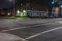 a large apartment building that has cars on the street at night time in the city