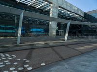 a sidewalk next to a road and a building with many windows and some columns and a walkway covered in polka dots