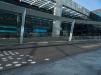 a sidewalk next to a road and a building with many windows and some columns and a walkway covered in polka dots