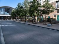 a city street is empty, with benches outside it and an area next to the sidewalk that extends into the building