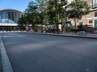 a city street is empty, with benches outside it and an area next to the sidewalk that extends into the building