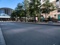 a city street is empty, with benches outside it and an area next to the sidewalk that extends into the building