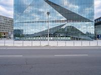 a photo taken from the road looking at a building that is reflecting other buildings and some cars