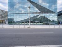 a photo taken from the road looking at a building that is reflecting other buildings and some cars