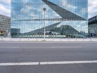 a photo taken from the road looking at a building that is reflecting other buildings and some cars