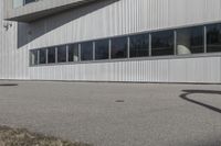 a stop sign on the side of the road next to an empty parking lot and an industrial building