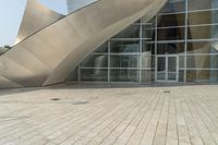 a view of a building that has a glass entrance and a stone pathway between it