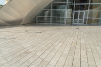 a view of a building that has a glass entrance and a stone pathway between it