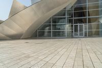 a view of a building that has a glass entrance and a stone pathway between it