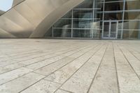 a view of a building that has a glass entrance and a stone pathway between it