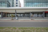 the empty bus stop sits near many buildings on the corner of the street and outside the windows