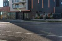 a black fire hydrant in front of an apartment building in an empty street space