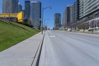 a empty city street in a large city with high rise skyscrapers behind it and some empty parking meters