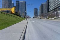 a empty city street in a large city with high rise skyscrapers behind it and some empty parking meters