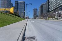 a empty city street in a large city with high rise skyscrapers behind it and some empty parking meters