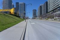 a empty city street in a large city with high rise skyscrapers behind it and some empty parking meters