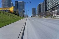 a empty city street in a large city with high rise skyscrapers behind it and some empty parking meters