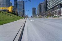 a empty city street in a large city with high rise skyscrapers behind it and some empty parking meters