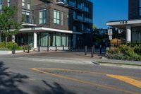 a city block that has several buildings and plants on each side of the street with trees in the corner