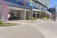 a picture of a building with parking space in between buildings by the street, and some pink flowers