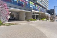 a picture of a building with parking space in between buildings by the street, and some pink flowers