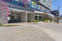 a picture of a building with parking space in between buildings by the street, and some pink flowers