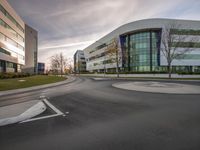 a road near the building with the corner curved up to it's left and an angled view of another building beyond