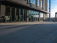 a person on a skate board walking by the corner of the street outside of a building