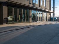 a person on a skate board walking by the corner of the street outside of a building