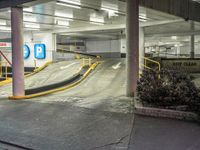 an empty parking garage with a ramp going through the middle of it and cars parked on either side of the stairs